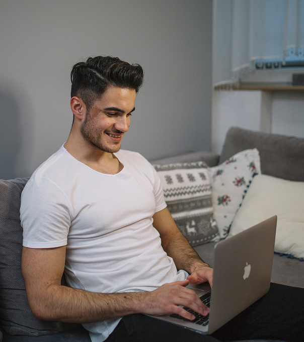smiling-man-using-laptop-couch 1